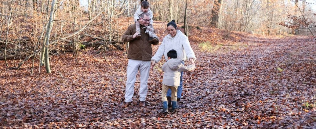 Family walking on a leaf-covered path in autumn woods