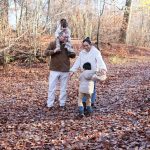 Family walking on a leaf-covered path in autumn woods